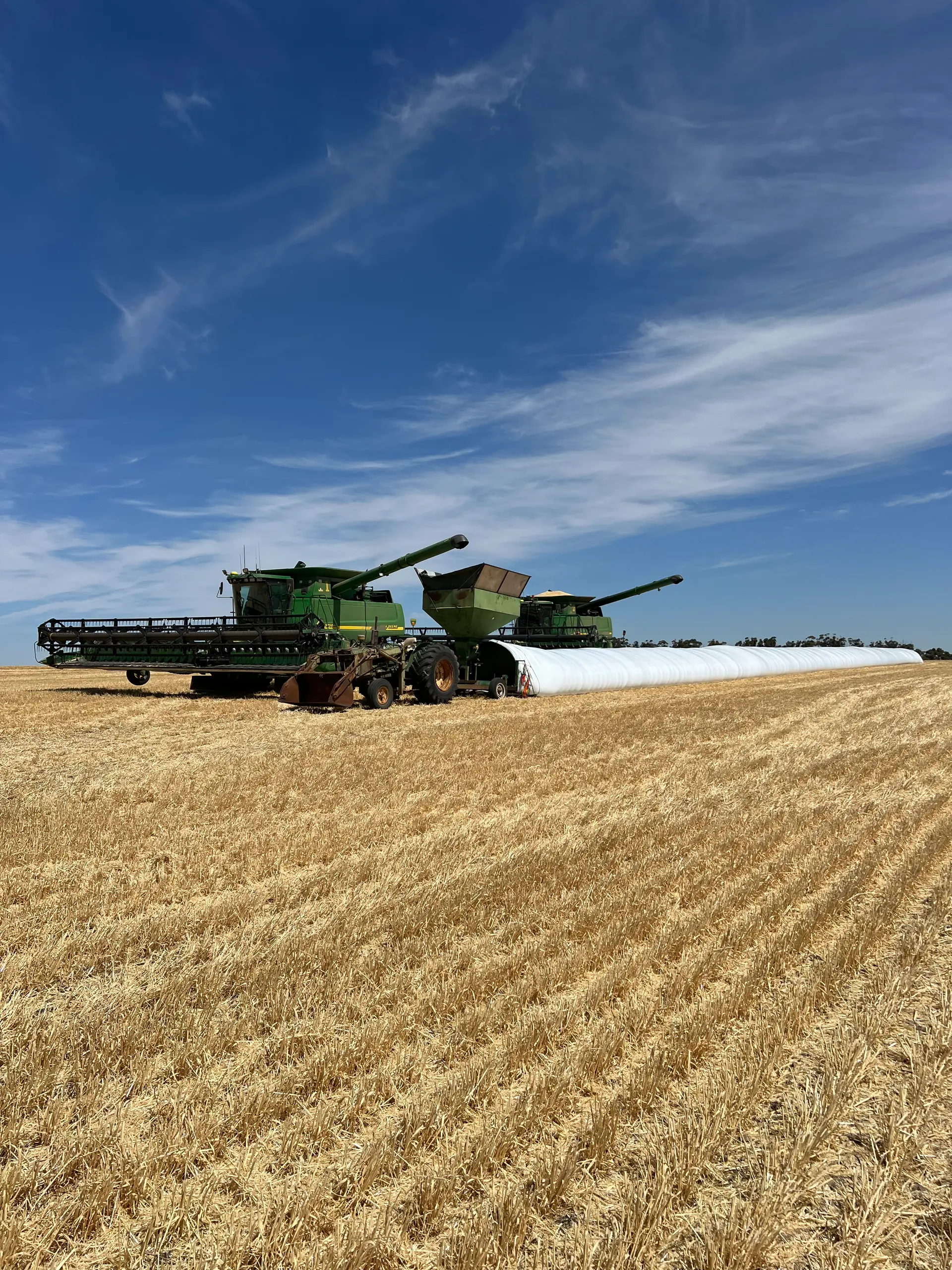 Headers unloading grain into on-farm storage